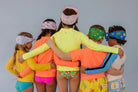 Group of children wearing colorful swimwear and headbands against a gray background