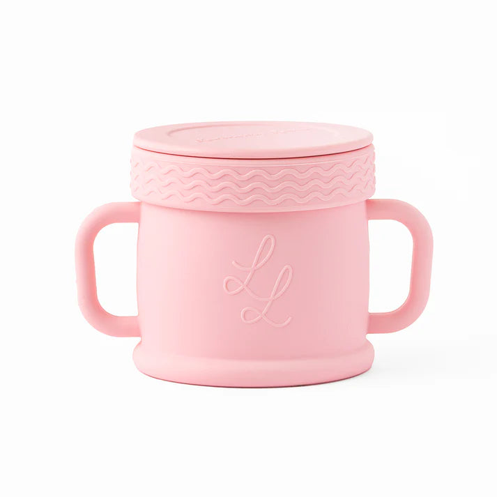 Pink children's cup with handles and textured lid on a white background