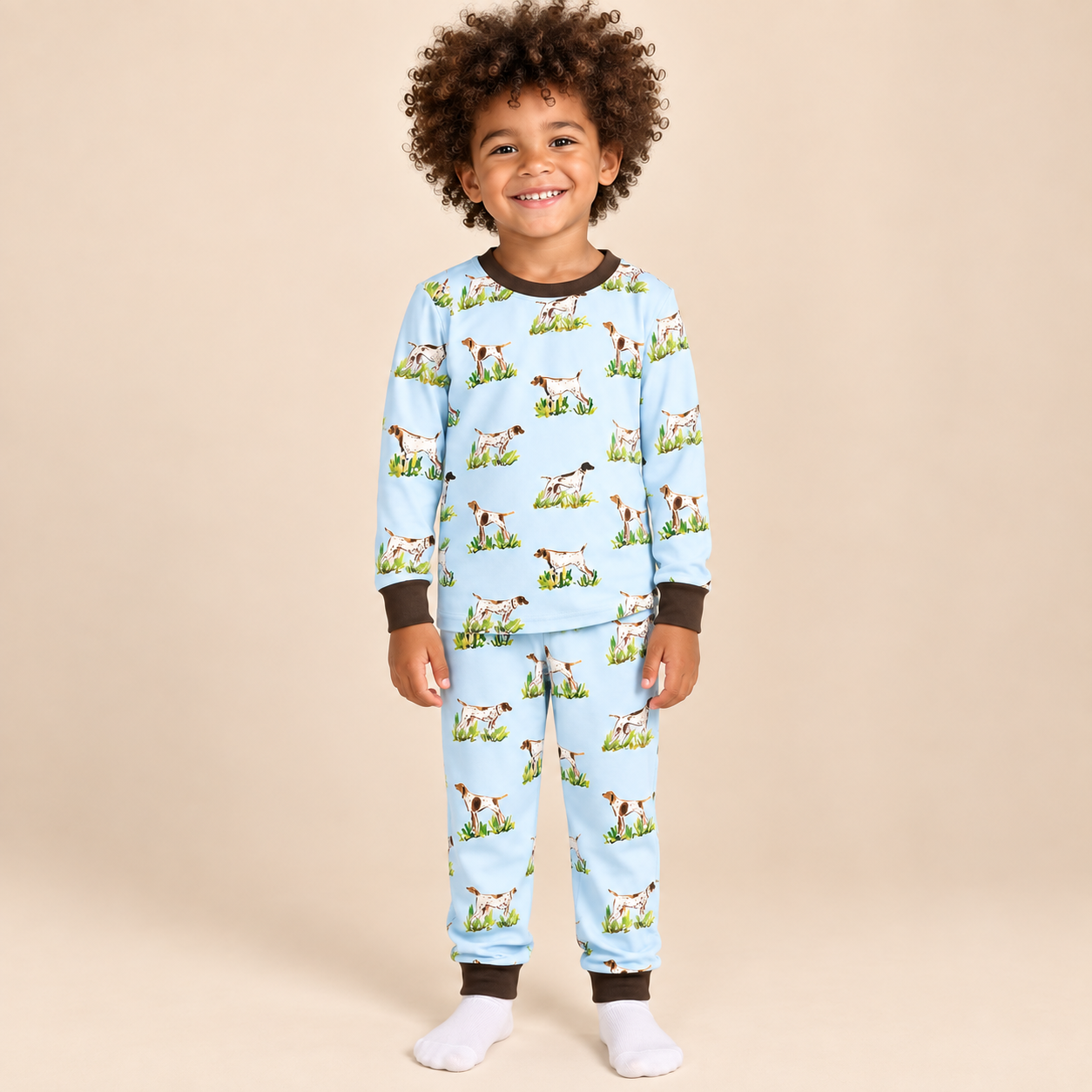 Boy wearing a light blue bird dog print bamboo lounge set with long sleeves, matching pants, and dark brown neckline and cuffs.