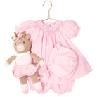 Pink baby dress with matching teddy bear on a hanger against a white background