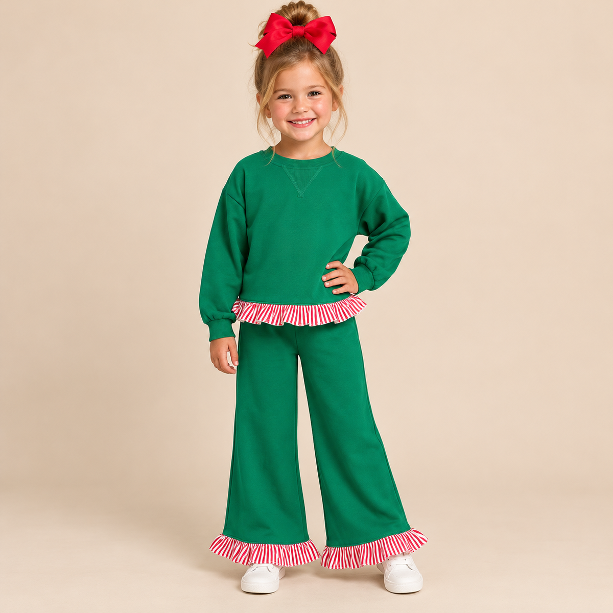 Young girl wearing a long sleeve green pant set with red and white trim.