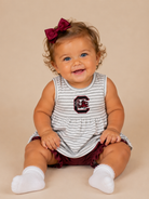 Baby wearing a gray and white striped dress with a South Carolina logo on a beige background