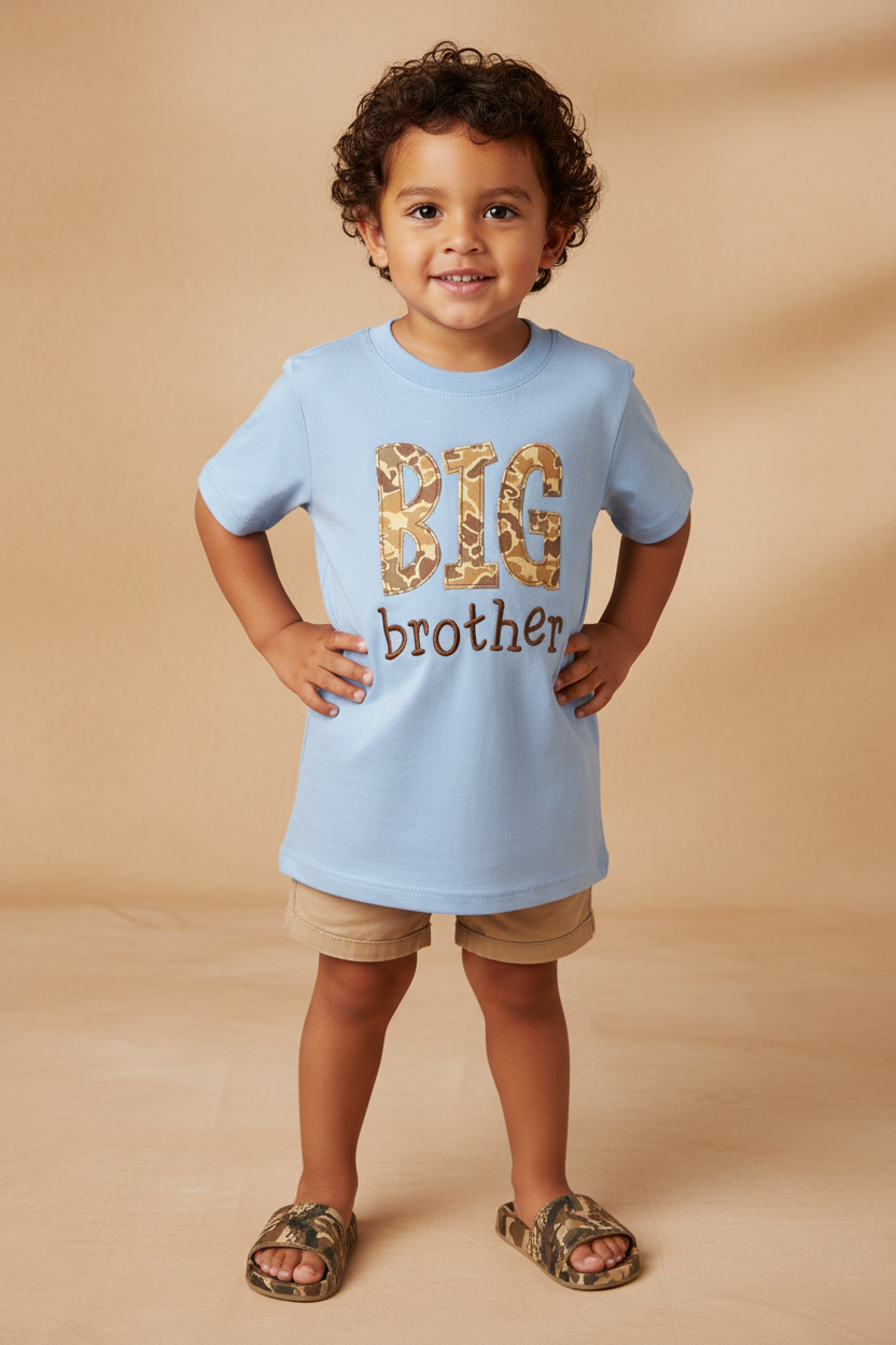 Boy standing with a blue BIG BROTHER embroidery shirt on beige background.