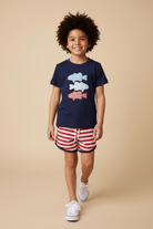 Boy model wearing a patriotic 3 fish navy shirt with red and white shorts. 