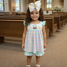 Young girl in a pastel checkered short set with a large bow in a church setting