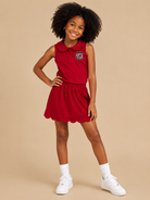 Young girl wearing a red dress with a logo on a beige background