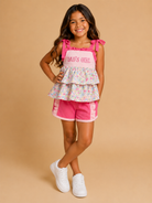 Young girl wearing a pink and floral outfit with 'Dad's Girl' text on a beige background