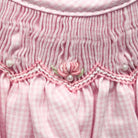 Close-up of a pink textured fabric with floral embroidery and pearl embellishments.