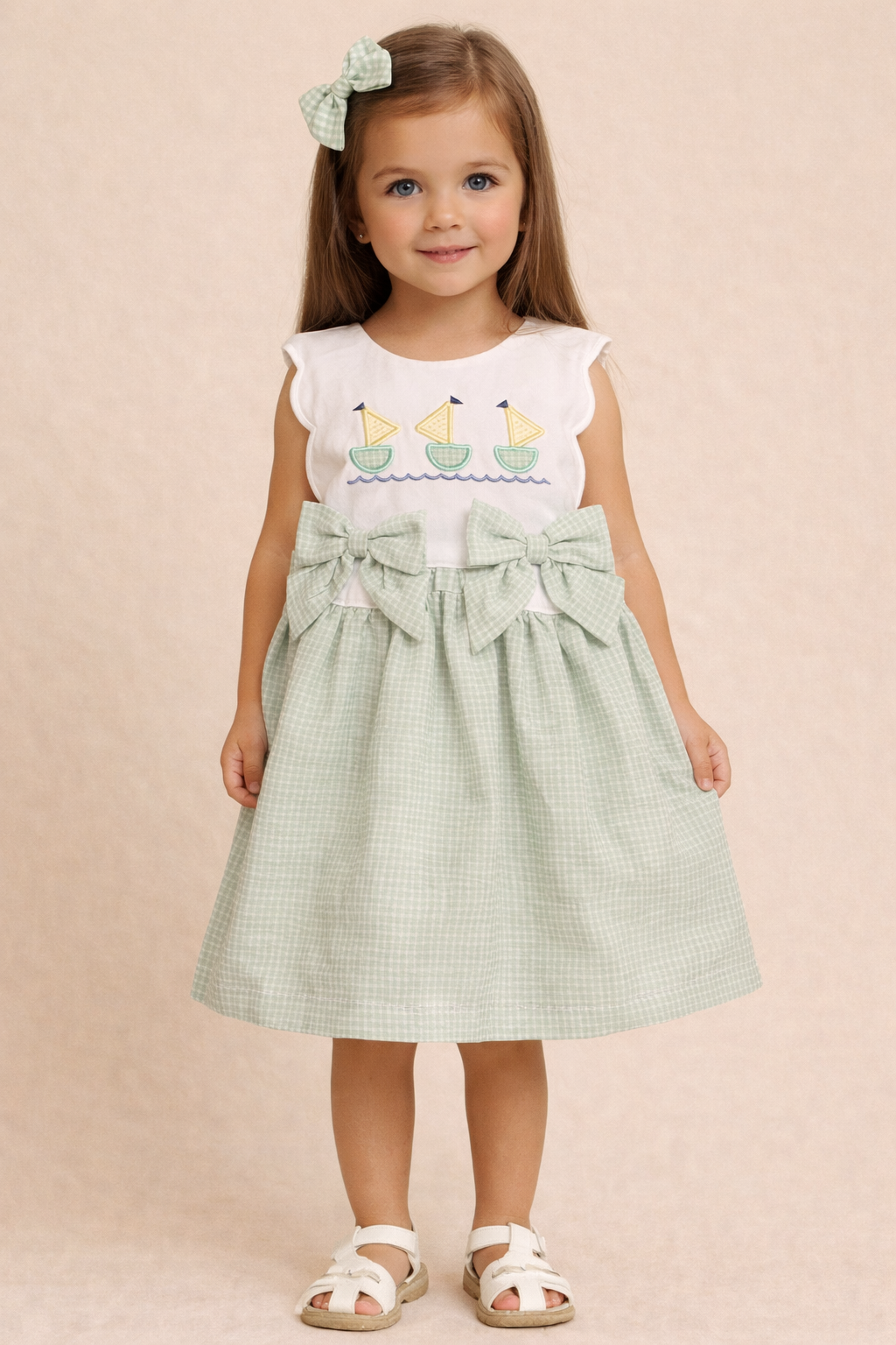 Young girl wearing a white top with sailboat design and a green checkered skirt on a beige background