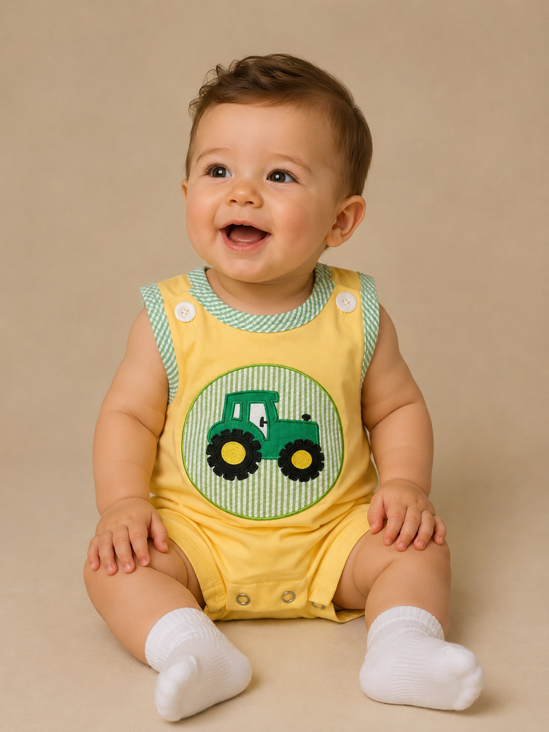 Baby wearing a yellow bubble with a green tractor design on a beige background