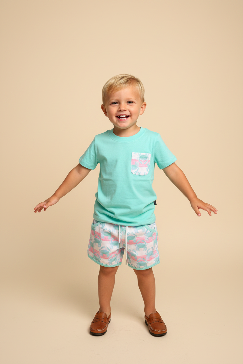 Toddler boy wearing aqua mint shirt with crab print pocket and matching shorts.