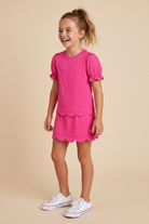 Young girl wearing a hot pink short sleeve skort set.