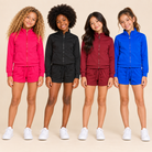 Four tween girls wearing athletic sets on a beige background.