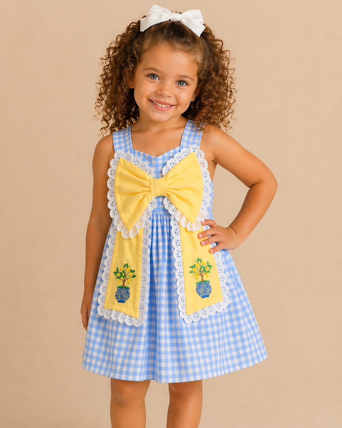 Young girl wearing a blue checkered dress with a yellow bow and floral design on a beige background