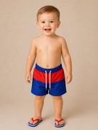 Child wearing red and blue swim shorts on a beige background