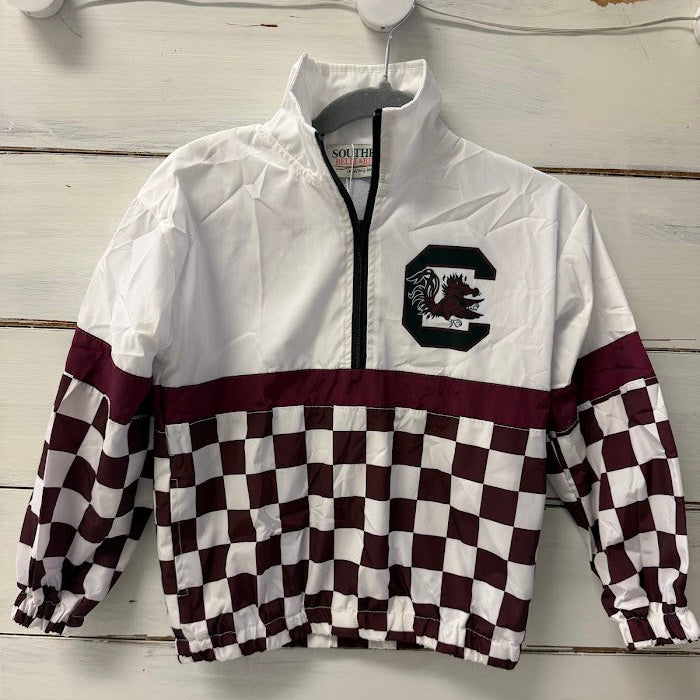 A white and maroon checkered quarter-zip windbreaker jacket hanging on a white wooden wall. The jacket features a solid white upper section, a maroon horizontal stripe, and a maroon and white checkerboard pattern across the lower body and sleeves.