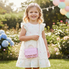 Little girl carrying pink shimmer sequin purse in spring setting