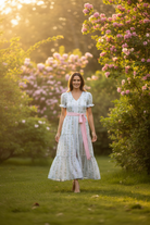 Woman in a light dress standing in a garden with blooming trees