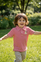 Boy wearing red stripe patriotic dog polo playing outdoors on green grass