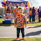 Boy wearing Tiger Cub Polo at game day tailgate with orange and purple decorations