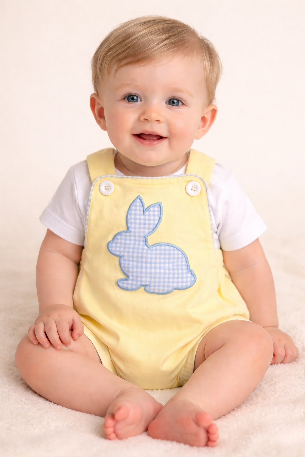 Baby wearing a yellow romper with a blue bunny design on a beige background