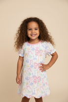 Toddler girl full body hand on hip wearing Girls Bow Show Sister Dress on beige background