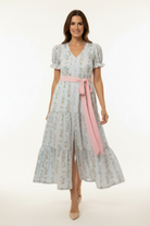 Woman wearing a floral dress with a pink belt on a white background