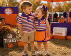Boy and girl wearing matching orange and purple stripe mascot outfits at Clemson tailgate
