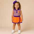 Toddler girl wearing orange and purple stripe mascot skort set at stadium