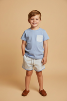 Boy wearing light blue boy short set with hand in pocket.